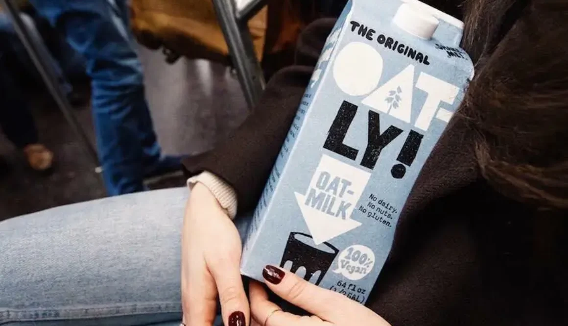 A box of Oatly in the hand of a women sitting down.