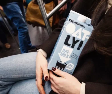 A box of Oatly in the hand of a women sitting down.